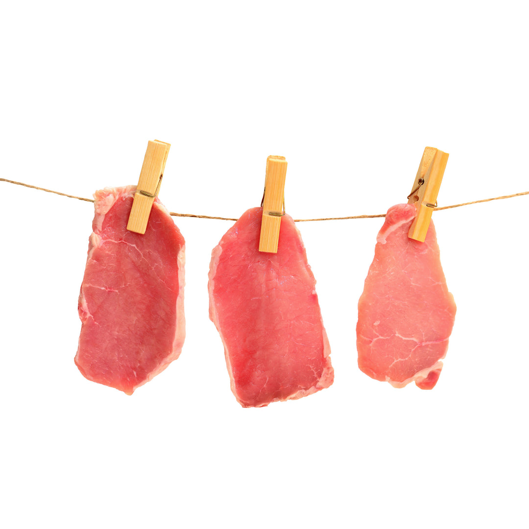 Raw pork chops hanging on a clothes line