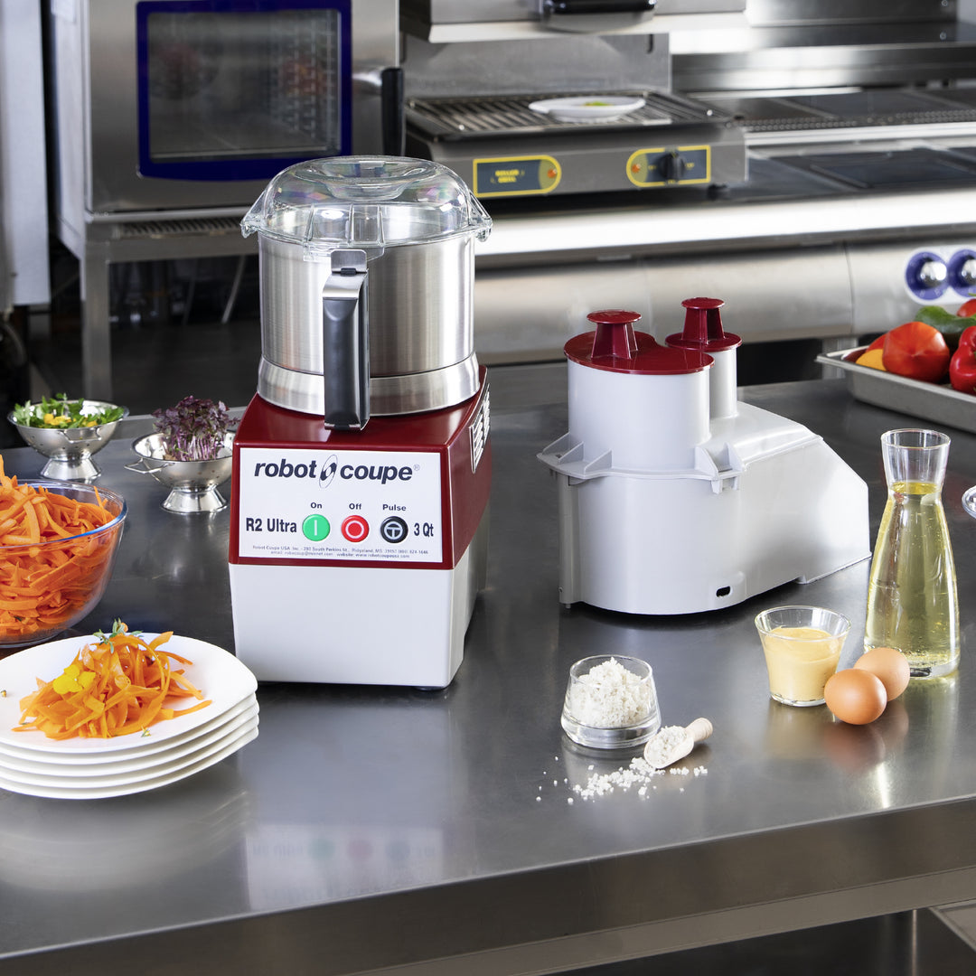 Robot Coupe R2N Vegetable Preparation Machine in use on a commercial kitchen work table