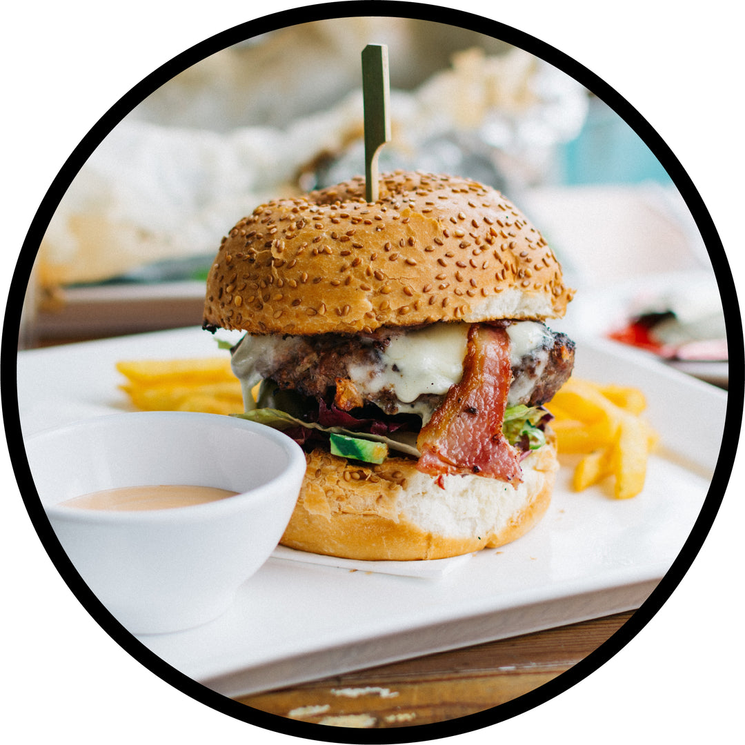 Gourmet burger, fries and dipping sauce presented on modern china platter and bowl