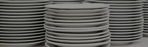 Stacks of white china dinner plates