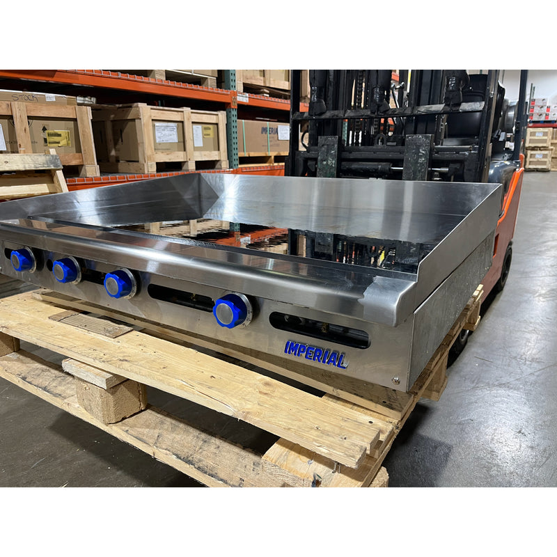 Front-side view of the manufacturer sticker and knobs of a USED 48” W x 30" D Thermostatic Commercial Griddle with 1" Thick Chrome Mirror Finish Flat Top Nat. Gas (Imperial ITG4830CG)